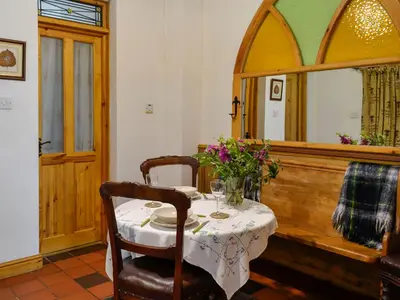 a dining room with a table and a mirror at Church Cottage in Rigg