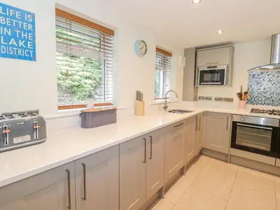 a large kitchen with white cabinets and a sink at Ladstock Cottage in Keswick