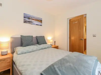 a bedroom with a bed and two lamps and a door at Ladstock Cottage in Keswick
