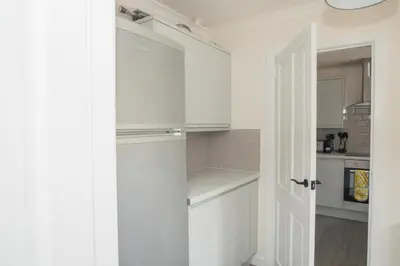 a kitchen with white cabinets and a white door at Tig Cottage - a rural, quirky, pet friendly 2 bedroom cottage near Ballantrae in Ballantrae