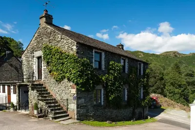 an old stone house with ivy growing on it at Jontys Cottage in Ambleside