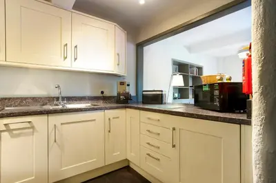a kitchen with white cabinets and a microwave at Jontys Cottage in Ambleside