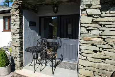 a table and chair sitting on the porch of a house at Jontys Cottage in Ambleside