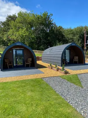 a large dome shaped building with chairs in the grass at Craigend Farm Holiday Pods - The Woolly Sheep in Dumfries