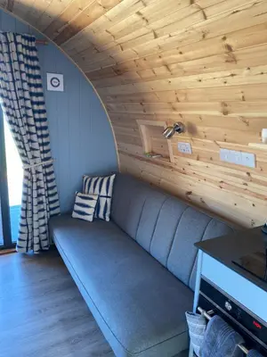 a couch in a room with a wooden ceiling at Craigend Farm Holiday Pods - The Woolly Sheep in Dumfries