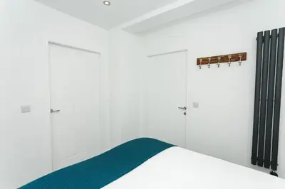 a bedroom with white walls and a bed with green sheets at Sea Glass Lodge in Gatehouse of Fleet