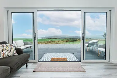 a living room with sliding glass doors to a patio at Sea Glass Lodge in Gatehouse of Fleet