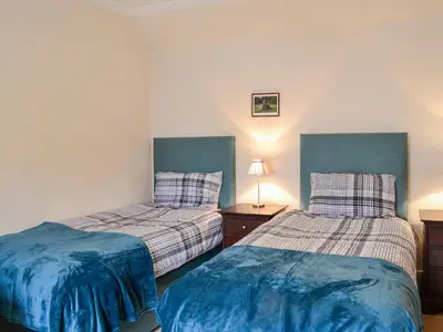two beds in a room with blue and white at The Moorings in Lochmaben
