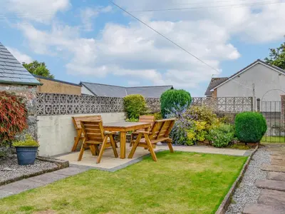 a wooden table and chairs in a garden at The Moorings in Lochmaben
