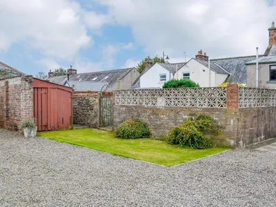 a brick retaining wall with a red gate and a yard at The Moorings in Lochmaben