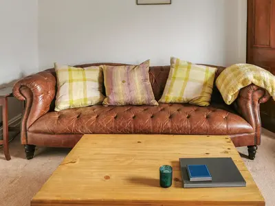 a brown leather couch with pillows and a coffee table at The Moorings in Lochmaben