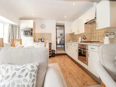 a kitchen and living room with a couch and a table at Woodloft Cottage in Elterwater