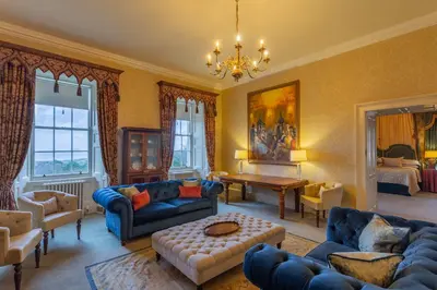 a living room with blue furniture and a chandelier at Glenapp Castle in Ballantrae