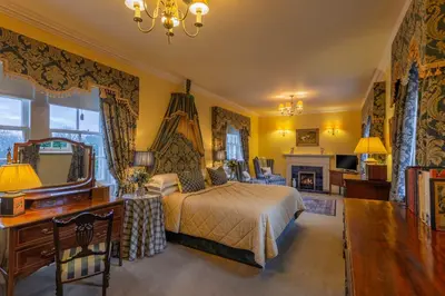 a bedroom with a bed and a desk and a mirror at Glenapp Castle in Ballantrae