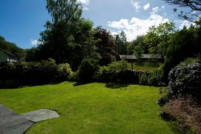 a yard with green grass and trees and a pond at Oak Cottage Chapel Stile in Chapel Stile