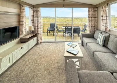 a living room with a couch and a tv and a table at Sandgreen Caravan Park in Girthon