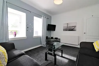 a living room with a couch and a glass table at Signature - Kirkhill Middle in Kirkmuirhill