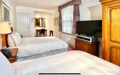 a hotel room with two beds and a flat screen tv at Promenade House in Douglas