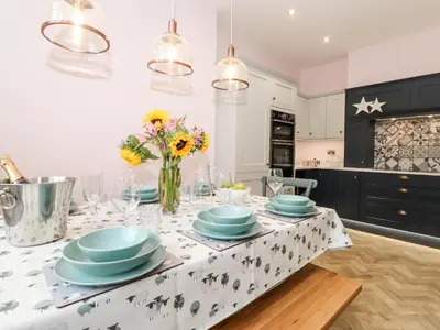 a kitchen with a table with plates and flowers on it at Eller Close House in Ambleside