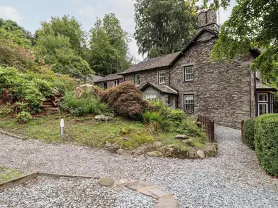 an old stone house with a gravel driveway at Eller Close House in Ambleside
