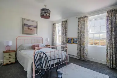 a bedroom with a bed and a chair and a window at 3 Clarks Terrace in Maryport