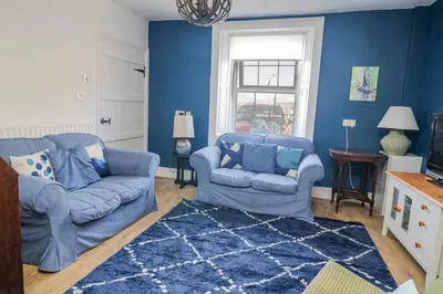 a blue living room with two blue couches and a rug at 3 Clarks Terrace in Maryport
