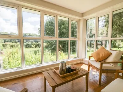 a living room with large windows and a coffee table at Caldhu Cottage in Holmrook