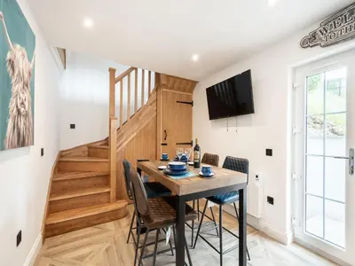 a dining room with a table and chairs and a staircase at The Railway Sleeper in Hyndfordbridge-end