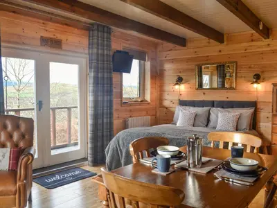 a bedroom with a bed and a table and chairs at Glenkens Lodge in Dalry