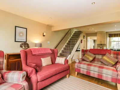 a living room with red chairs and a staircase at Scale Force in Keswick