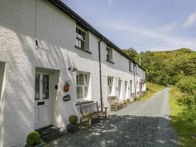 a row of white houses with a bench on a road at Scale Force in Keswick