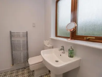 a bathroom with a sink and a mirror and a toilet at Ravenglass Retreat in Ravenglass