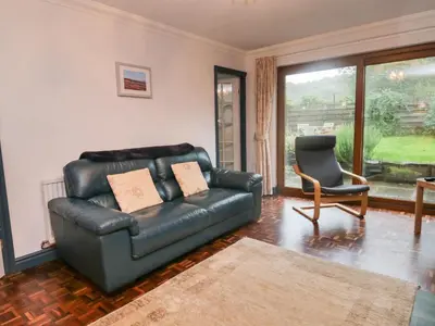 a living room with a leather couch and a chair at Ravenglass Retreat in Ravenglass