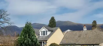a house with a roof with mountains in the background at Plum Cottage in Keswick