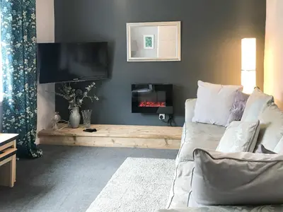a living room with a couch and a flat screen tv at Kitty's Cottage in Girvan