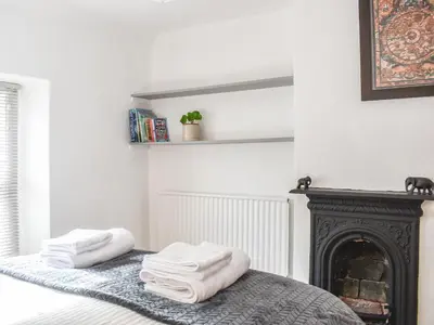 two towels sitting on a bed in a room with a fireplace at Riverside Cottage in Keswick