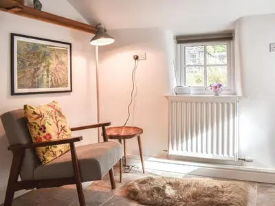 a living room with a chair and a window at Riverside Cottage in Keswick