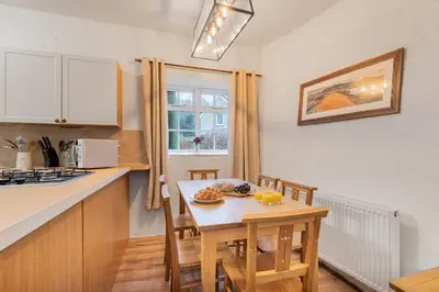 a kitchen with a table and chairs and a small table with oranges on it at Cottage 3 Old Farmhouse Mews in Keswick