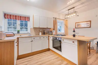 a kitchen with white cabinets and a counter top at Cottage 3 Old Farmhouse Mews in Keswick