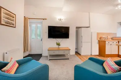 a living room with two blue couches and a tv at Cottage 3 Old Farmhouse Mews in Keswick