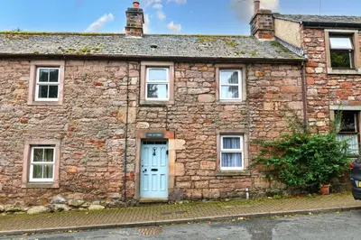 an old stone house with a blue door at Finest Retreats - The Cottage at Greystoke in Greystoke