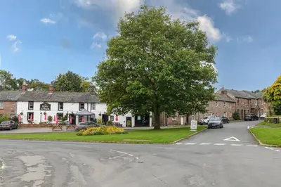 a street in a village with a tree and houses at Finest Retreats - The Cottage at Greystoke in Greystoke