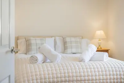 a white bed with towels and pillows on it at Cottage 8 Old Farmhouse braithwaite in Keswick