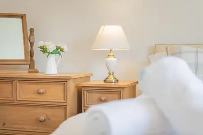 a bedroom with a lamp and a dresser with a mirror at Cottage 8 Old Farmhouse braithwaite in Keswick