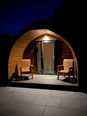 two benches sitting on a patio with an archway at Craigend Farm Holiday Pods - The Curly Coo in Dumfries