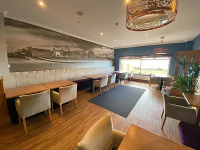 a restaurant with tables and chairs and a painting on the wall at The Calder House Hotel in Seascale