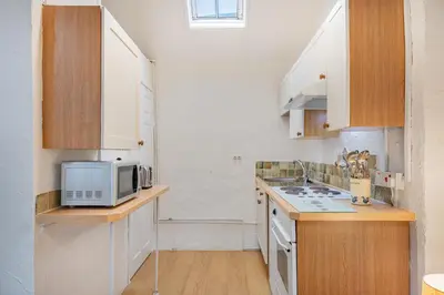a small kitchen with white cabinets and a microwave at Cottage 6 Studio Mews in Keswick