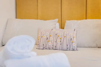 a bed with white pillows and a pillow on it at Cottage 6 Studio Mews in Keswick