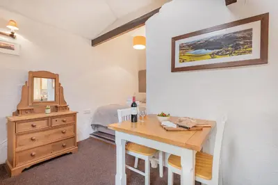 a room with a table and a bedroom with a bed at Cottage 6 Studio Mews in Keswick