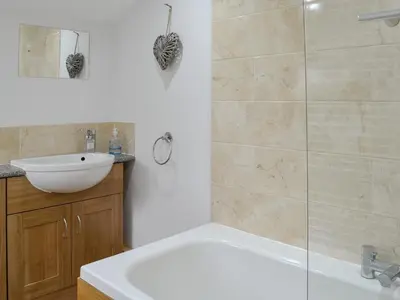 a bathroom with a white tub and a sink at Howbeck Cottage in Hesket Newmarket